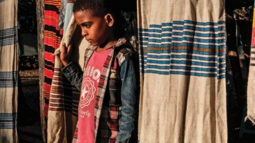 A child stands through a curtain of traditional fabrics in Alamata, Ethiopia, on December 8, 2020. - ...