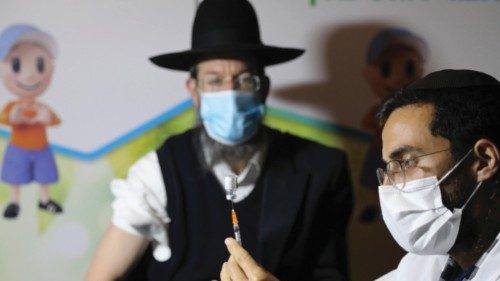epa08937702 An ultra-orthodox Jewish man receives a coronavirus COVID-19 pandemic vaccine by a male ...