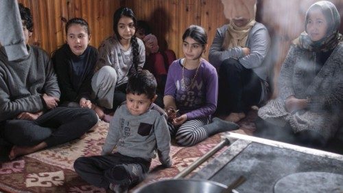 Migrant families from Iraq and Afghanistan sit inside an abandoned house where they live in the ...