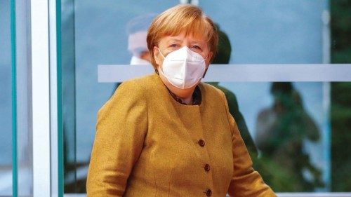 German Chancellor Angela Merkel wears a face mask as he takes her seat to hold a press conference on ...