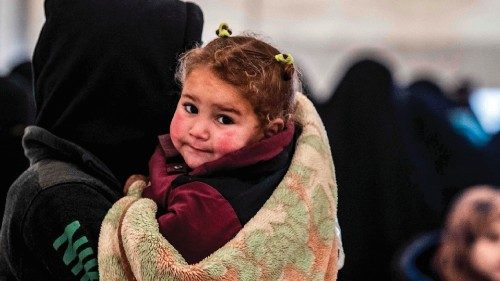 A veiled woman stands carrying a child alongside others during the release of persons suspected of ...