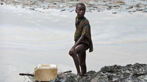 epa08972631 (FILE) - A boy with a fishnet standing on the oil stained bank of a creek near Goi, ...
