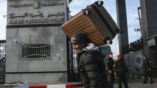 A man carries a suitcase on his shoulder while members of the Palestinian security forces loyal to ...