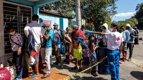 Venezuelan migrants wear a face masks as they queue to receive food and medicines from members of ...