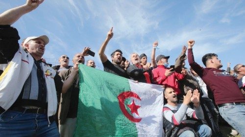 People gesture and carry a national flag outside the Kolea prison, west of the capital Algiers, ...