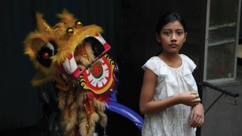 A girl stands next to a ceremonial Chinese Lion head on the street in Phnom Penh, Cambodia, February ...