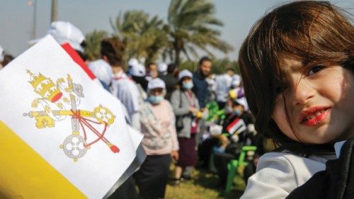 A girl holding the Vatican flag looks on as she waits for the arrival of Pope Francis, at Baghdad ...