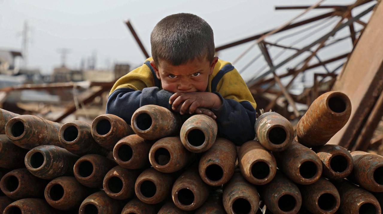 TOPSHOT - A Syrian child poses atop a stack of neutralised shells at a metal scrapyard on the ...