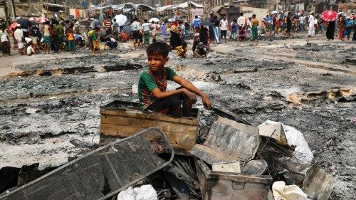 A Rohingya refugee boy sits on a stack of burned material after a massive fire broke out and ...