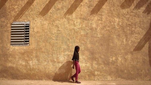 A young woman walks next to the wall of the great mosque of Konna on March 20, 2021. - Malian prime ...