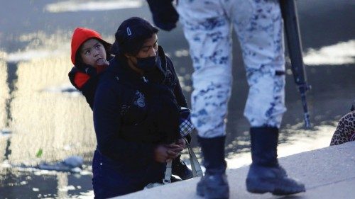A migrant boy looks to a member of the Guardia Nacional (National guard)  before crossing with his ...