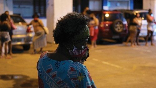 A resident of Rocinha slum carries a kid as she waits to receive donations from Bees of Love ...