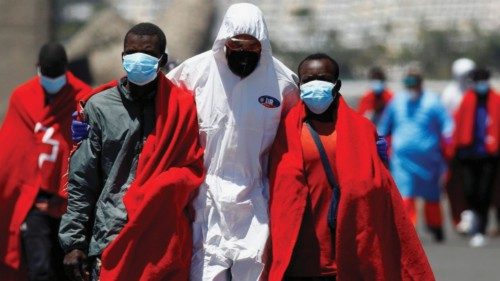 A rescuer helps migrants to walk, after being rescued by a vessel from the Spanish coast guard, in ...