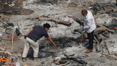 Parenti di vittime del Covid recuperano i resti dei propri cari dopo la cremazione dei corpi in cataste di legna fuori dai crematori (Reuters)