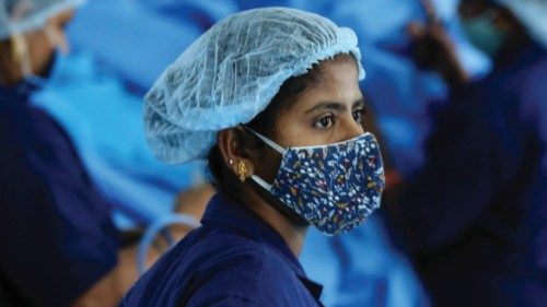 epa09180941 Indian laborers work at the Personal protective equipment (PPE) Kit production factory ...