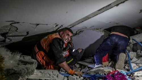 epa09203775 Palestinian civil defense men search for people in the rubble of a destroyed building ...