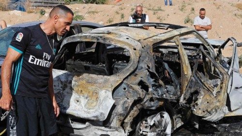 Onlookers gather around charred vehicles hit by rockets launched by Hamas militants from the Gaza ...