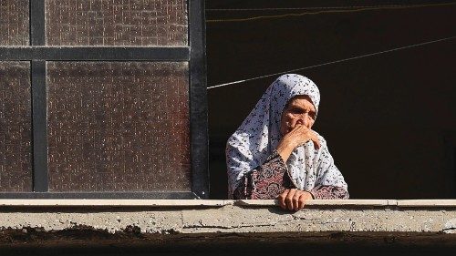 A Palestinian woman is pictured at the window of her house as she looks at destruction in Gaza City, ...