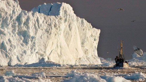 FILE PHOTO: A fishing boat sails past a large iceberg at the mouth of the Jakobshavns ice fjord near ...