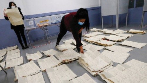 Poll workers wearing protective masks sort through and count the votes after polls closed during the ...