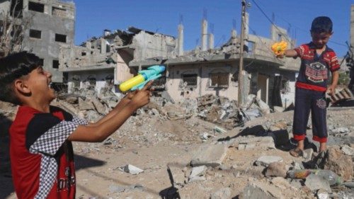 Palestinian children play with toy guns on May 24, 2021 next to the rubble of a house which was ...