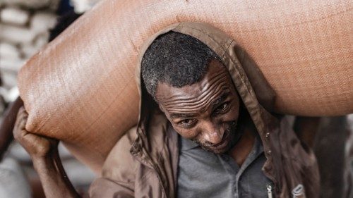 A worker carries a 100 kilos bag of red teff in a warehouse of a market in Addis Ababa, on June 12, ...