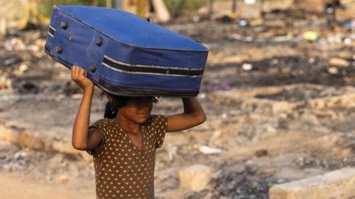 A Rohingya refugee carries her belongings to a temporary shelter after a fire destroyed a Rohingya ...