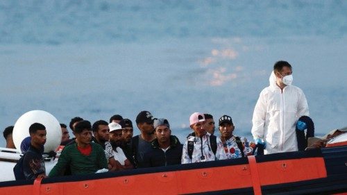 Migrants sit on board of an Italian coast guard boat before disembarking in the Sicilian island of ...