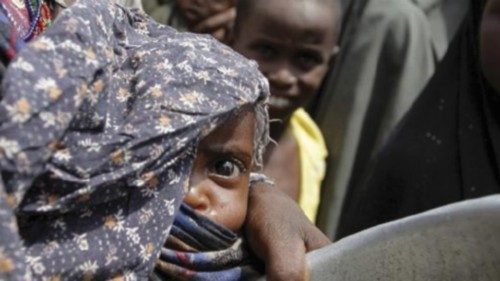 A woman carries her baby as she queues for food in a camp established by the Somali Transitional ...