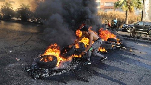 A Lebanese youth sets tires on fire during a protest at a main road in Lebanon's capital Beirut ...