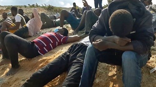 A video grab shows migrant survivors of a deadly shipwreck siting on a sandy beach on the coast of ...