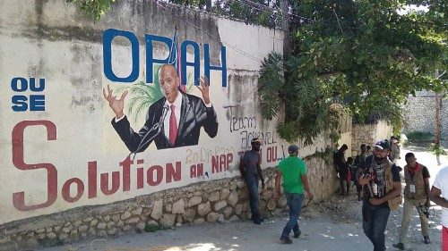 People walk past a wall with a mural depicting Haiti's President Jovenel Moise, after he was shot ...