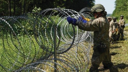 Soldati lituani dispongono filo spinato al confine  con il Belarus per fermare  il passaggio  dei migranti (Reuters) 