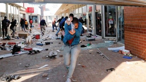 TOPSHOT - A man runs shielding his face as police open fire with rubber bullets at looters ...