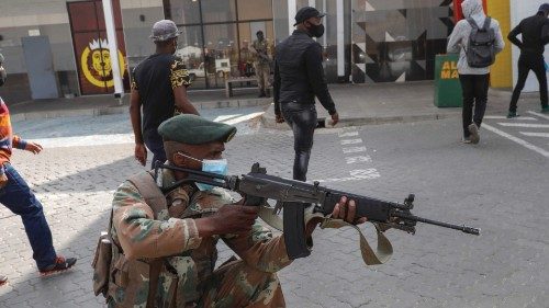 A member of the South African Defence Force (SANDF) keeps watch as people queue to continue shopping ... A member of the South African Defence Force (SANDF) keeps watch as people queue to continue shopping ...