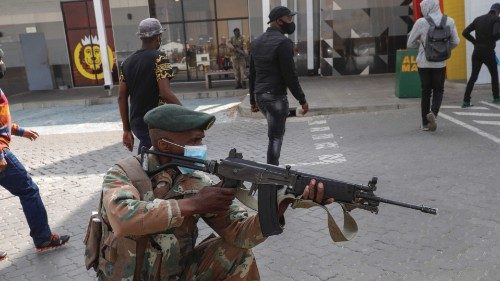 A member of the South African Defence Force (SANDF) keeps watch as people queue to continue shopping ...