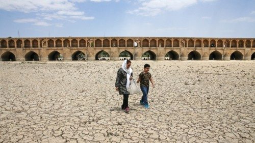 In this Tuesday, July 10, 2018 photo, a woman and a boy walk on the dried up riverbed of the ...