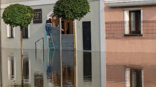 Two people seal the entrance of a cafe with a special flood barrier to protect the building from the ...