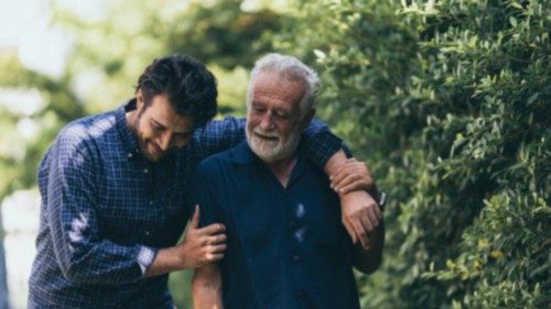 The old man and his son are walking in the park. A man hugs his elderly father. They are happy and ...
