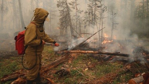 A specialist of the local forest protection service works to extinguish a forest fire near the ...