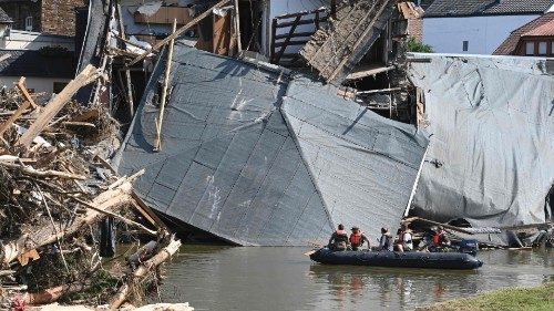 TOPSHOT - Military personnel floats on a boat on the Ahr river as the roof of a damaged house hangs ...