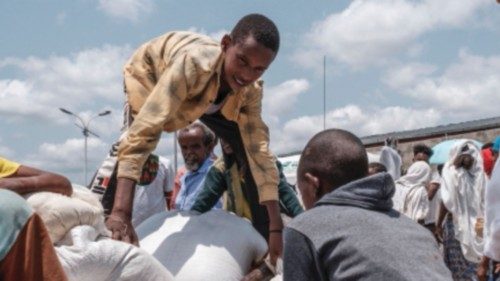 (FILES) In this file photo taken on July 11, 2021 a youngster arranges a sack of wheat on a cart ...