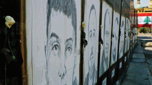 White roses are seen on portraits of victims of last year's Beirut port blast in the Lebanese ...