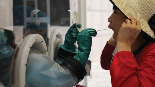 A medical worker collects a swab from a woman at a mobile nucleic acid testing site outside a ...