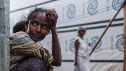 An internally displaced woman looks on as she sits next to her shelter in a camp in the town of ...