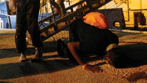 A migrant prays on the ground after disembarking from the German NGO migrant rescue ship Sea-Watch 3 ...