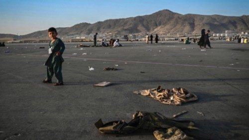 An Afghan child walks near military uniforms as he with elders wait to leave the Kabul airport in ...