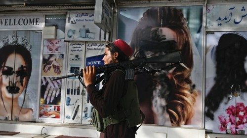 TOPSHOT - A Taliban fighter walks past a beauty salon with images of women defaced using spray paint ...