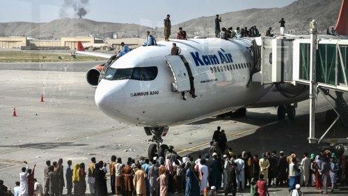 Afghan people climb atop a plane as they wait at the Kabul airport in Kabul on August 16, 2021, ...