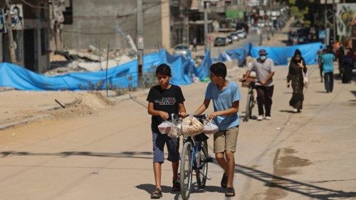 Palestinians walk with their bicycles along a cordoned off neighborhood that was destroyed by ...